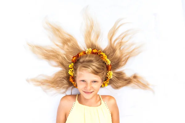 Adorável criança sorridente com cabelos louros longos saudáveis e fortes em forma de sol adornado com flores como espaço de cópia de faixa de cabeça — Fotografia de Stock