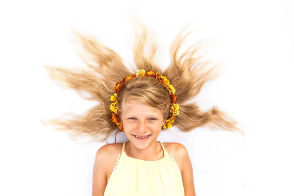 Criança sorridente com cabelos louros longos saudáveis e fortes em forma de sol adornado com flores espaço de cópia — Fotografia de Stock