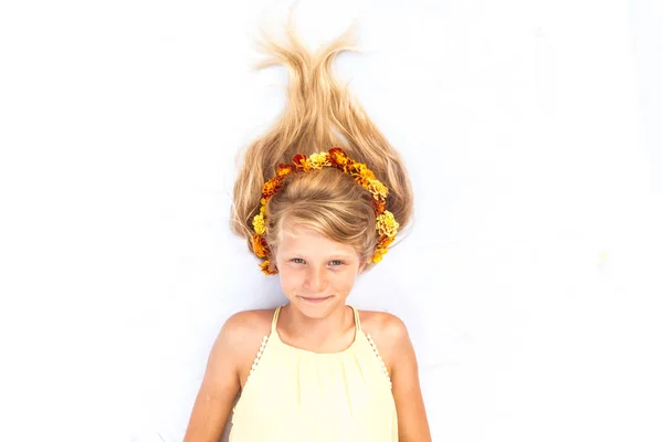 Schattig lachend kind met gezond en sterk lang blond haar in de vorm van vreugdevuur versierd met bloemen hoofdband kopieerruimte — Stockfoto