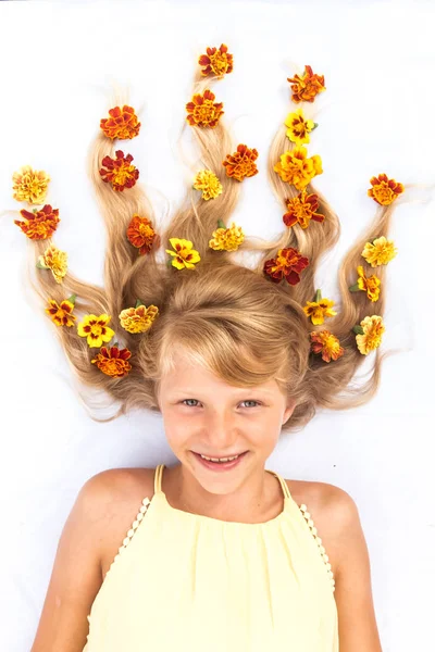 Adorable niño sonriente con cabello rubio largo sano y fuerte en forma de fuego con arreglo floral — Foto de Stock