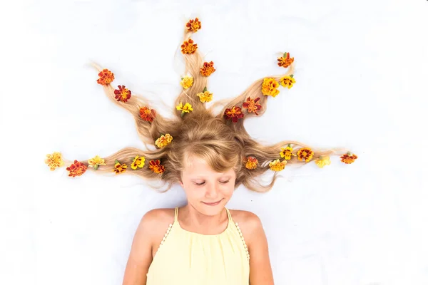 Encantador niño sonriente con cabello rubio largo sano y fuerte en forma de espiga con arreglo floral —  Fotos de Stock