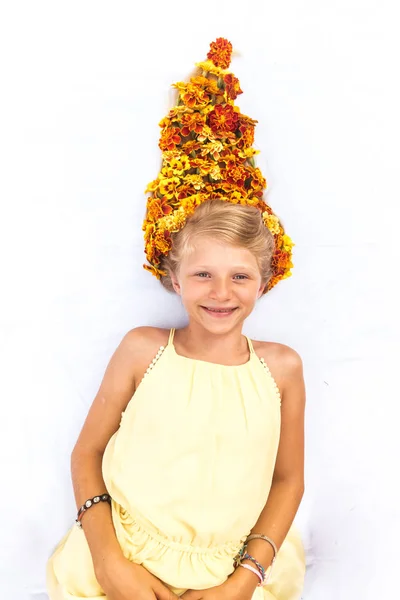 Encantadora criança sorridente com cabelos loiros longos saudáveis e fortes em forma de fogueira com arranjo floral — Fotografia de Stock