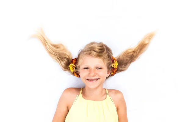Красивый улыбающийся ребенок с забавной прической, украшенной цветами — стоковое фото
