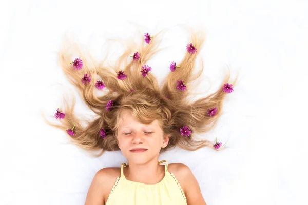 Очаровательный ребенок со здоровыми и сильными длинными светлыми волосами в форме солнца, украшенными цветочными идеями — стоковое фото