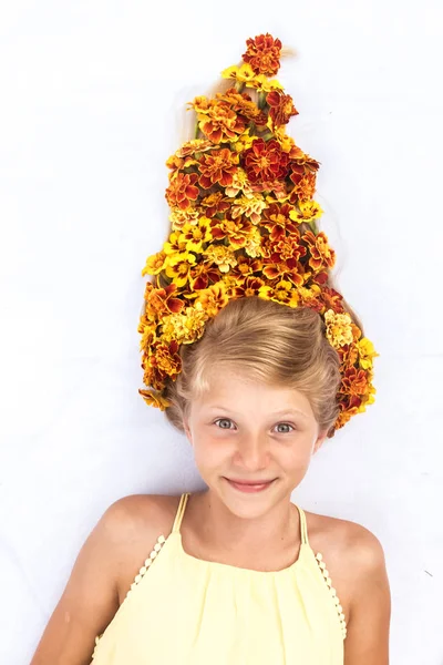 Charmigt leende barn med frisk och stark lång blond hår i form av bål med blomsterarrangemang — Stockfoto