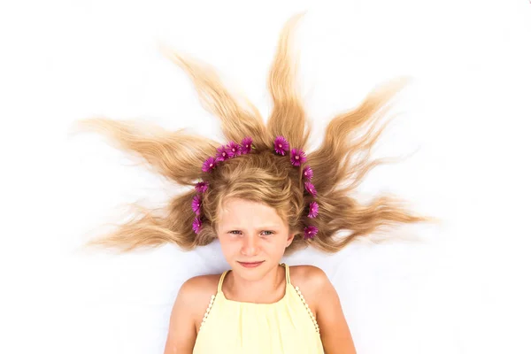 Adorável criança sorridente com cabelos louros longos saudáveis e fortes em forma de sol adornado com headband floral — Fotografia de Stock