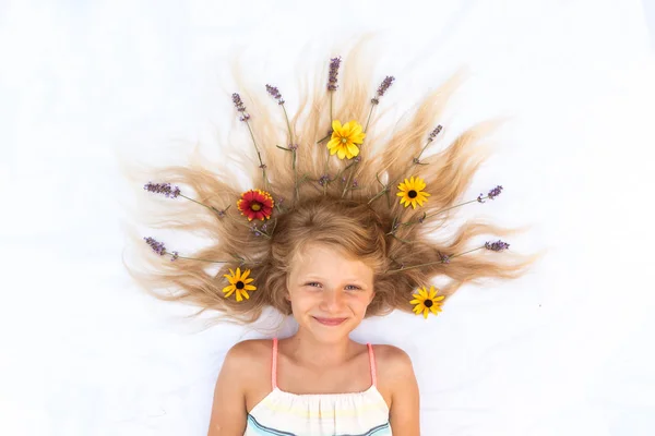 Lindo niño con pelo largo y rubio estilizado con decoración floral de lavanda y gerbera, disparado desde la perspectiva de las aves —  Fotos de Stock