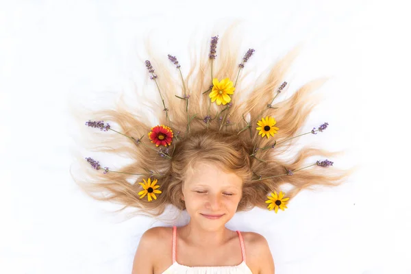 Cute child with long blond hair stylized with lavender and gerbera floral decoration, shot from birds perspective — Stock Photo, Image