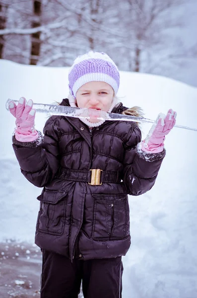 Liten flicka slickar frysta istappar — Stockfoto