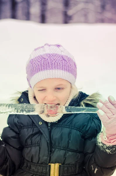 Litet barn slickar frusen istapp — Stockfoto