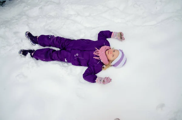 Bambina sdraiata nella neve — Foto Stock