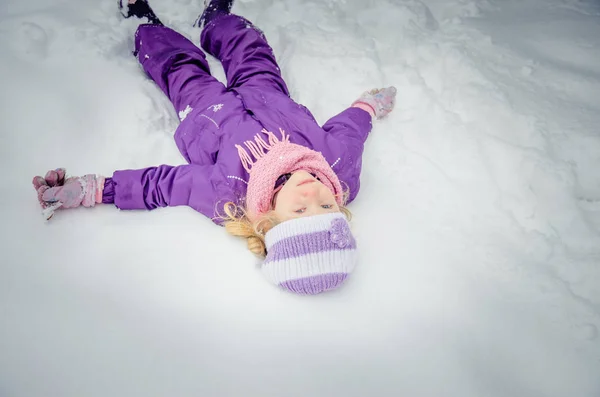 Küçük kız karda yatıyor. — Stok fotoğraf