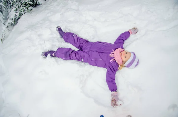 Liten flicka som ligger i snö — Stockfoto