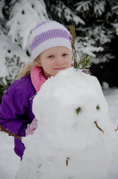 Tonåring barn har kul i glad vinter skog vit bulding en snögubbe staty — Stockfoto