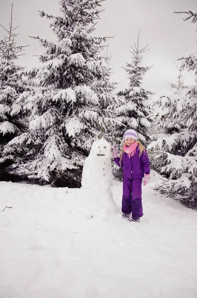 Genç çocuk mutlu kış ormanlarında eğleniyor. Kardan adam heykeli yapıyor. — Stok fotoğraf