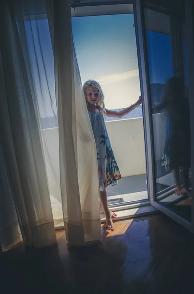 Niño en el balcón detrás de la cortina — Foto de Stock