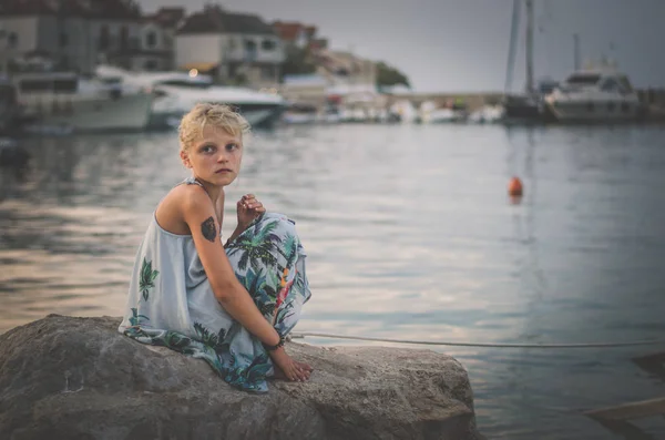 Маленький ребенок в одиночестве сидит в большом камне на берегу моря — стоковое фото