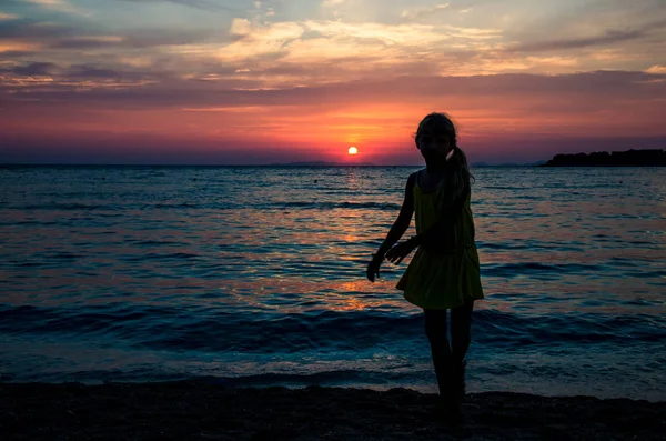 Silhouette de fille et coucher de soleil orange coloré — Photo