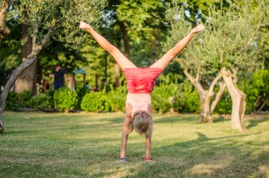 Küçük çocuk yeşil parkta ayaklarının üzerinde duruyor.