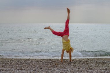 Aktif çocuk deniz kıyısında renkli günbatımında spor yapıyor.
