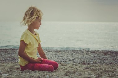 Güzel sarışın kız deniz kenarında yalnız başına dinleniyor.