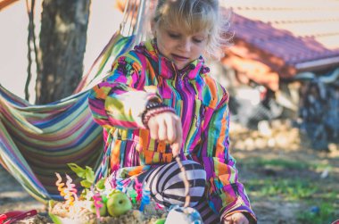 Oyun bahçesindeki sevimli kız kumdan kek pişiriyor.