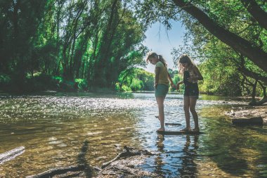 Güneşli yaz gününde sığ sularda suyla oynayan iki küçük kız.