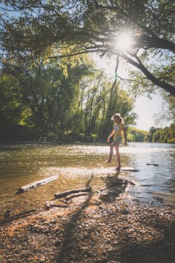 Güneşli yaz gününde nehirde su sıçratan tatlı kız.