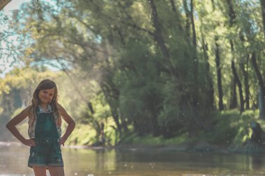 Romantik yeşil bir ortamda, altın saatinde hala çocuk. Etrafında nehir var.
