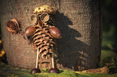 Çam kozalağı, meşe palamudu, yapraklar ve çiçeklerin canlı sonbahar renklerinden sevimli bir figür.