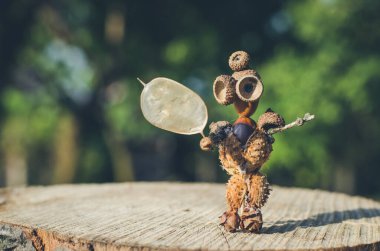 Kestaneden tatlı bir figür, yapraklar ve çiçekler canlı sonbahar renklerinde.