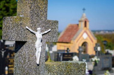 Mezarlıkta dinsel atmosfer ve arka planda haç sembolü ve kilise var.