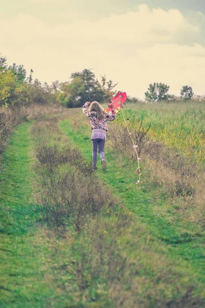 秋天阳光灿烂的时候 一个可爱的姑娘带着风筝在绿地里奔跑 — 图库照片