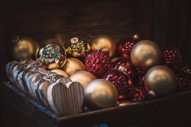Tahta bavulda düzenlenmiş Noel ağacı için altın ve kırmızı mücevherler.