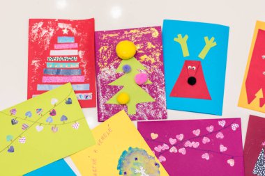 Ren geyiklerinin Noel kartları, Noel ağacı, masada yatan çocukların yaptığı karlar ve kalpler.