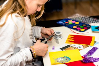 Renkli kağıtlar, makas, yapıştırıcı, kamış, kurdele, kurdele, dantel masa üzerinde Noel tebrik kartları oluşturmaya hazırlanıyor.