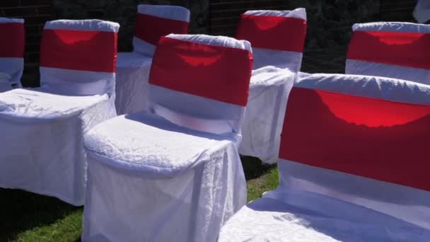用白色和红色布装饰的椅子矗立在绿草的草坪上 准备婚礼使用 轴电动云台稳定器拍摄 — 图库视频影像