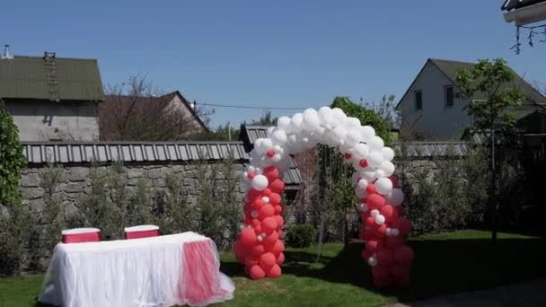 由红白气球制成的婚礼拱门 参观仪式 绿色草坪 — 图库视频影像