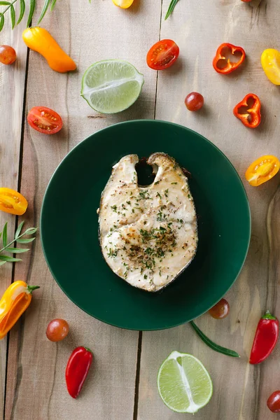 Fish steak on a green plate with vegetables — Stock Photo, Image