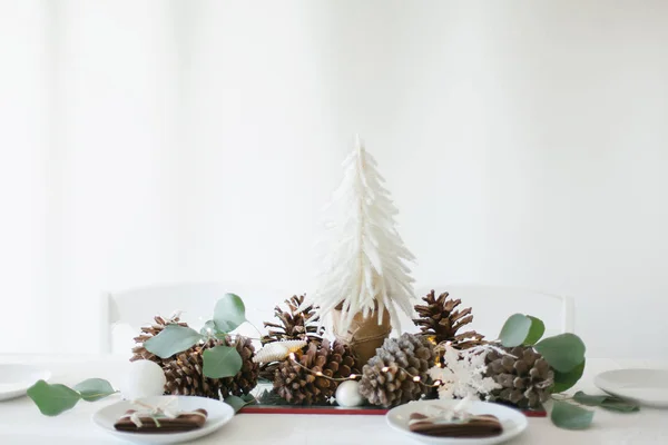 Winter table decoration with mini Christmas tree, pine cones and