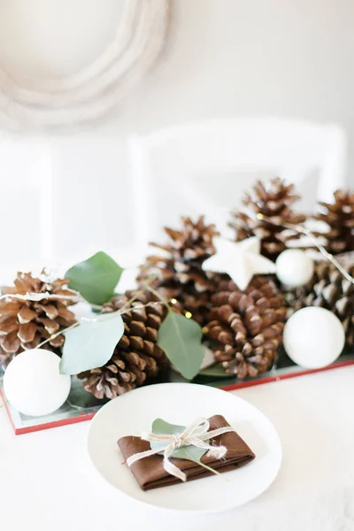 Kersttafel met dennenappels, witte ornamenten en rus — Stockfoto