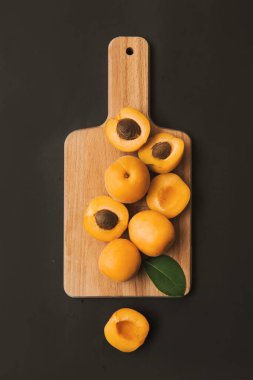 Siyah arka planda tahta kesim tahtası kayısı yarımları ve meyve kamışı. Taze yaz durgun hayat.