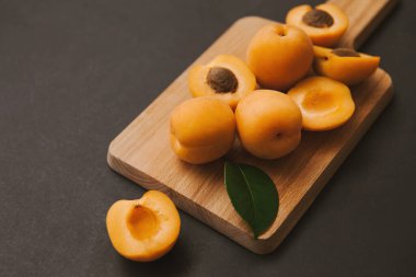 Siyah arka planda tahta kesim tahtası kayısı yarımları ve meyve kamışı. Taze yaz durgun hayat.