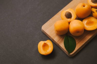 Siyah arka planda tahta kesim tahtası kayısı yarımları ve meyve kamışı. Taze yaz durgun hayat.