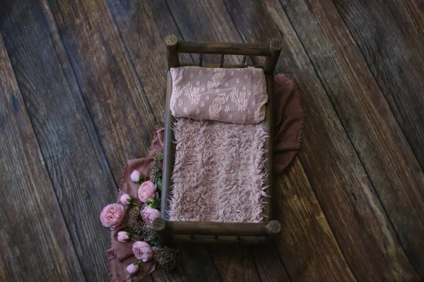 Yeni doğan dijital zemin - koyu ahşap yatak, pembe sahte kürk ve dantel yastık, siyah ahşap döşeme paspası, jüt ve pembe katman ve çiçek..