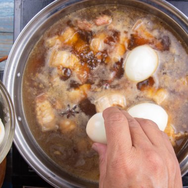 Çizgili domuz eti tencerede pişirme / tatlı kahverengi Komposto domuz eti sos (Moo Pa-lo) kavramı yemek için haşlanmış yumurta koyarak Şef