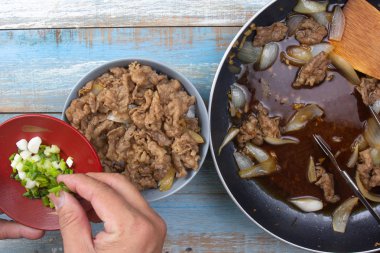 aşçı pirinç pişmiş sığır eti dilim soğan koymak / Japon yemek pişirme Gyudon kavramı