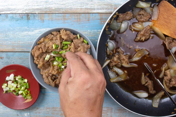 aşçı pirinç pişmiş sığır eti dilim soğan koymak / Japon yemek pişirme Gyudon kavramı