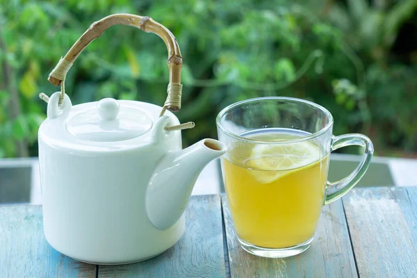 带有柠檬和茶壶的花园背景热茶杯 — 图库照片