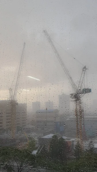 A crane in heavy rain is working on building a skyscraper